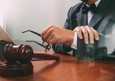 Man with suit sitting behind the wooden table holding glasses